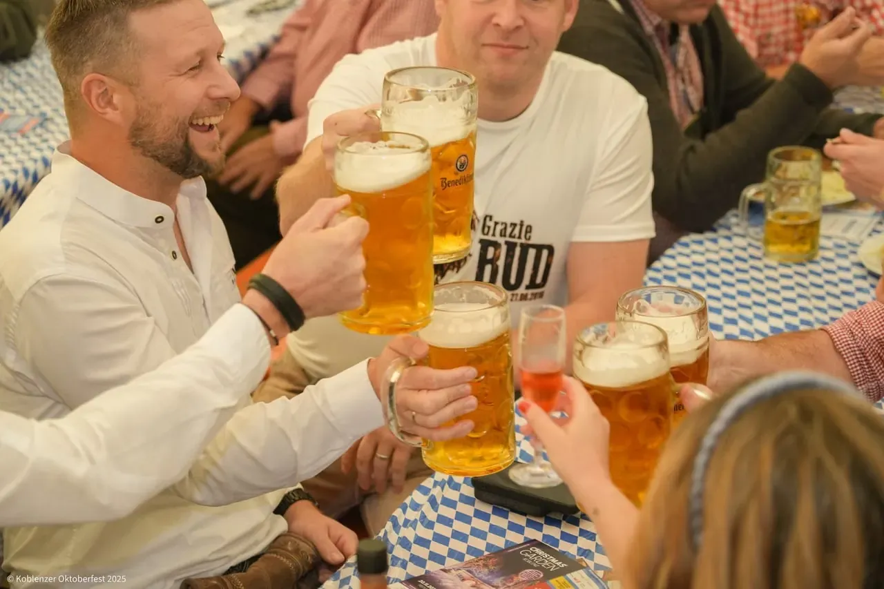 Gäste stoßen mit Maßkrügen im Festzelt an